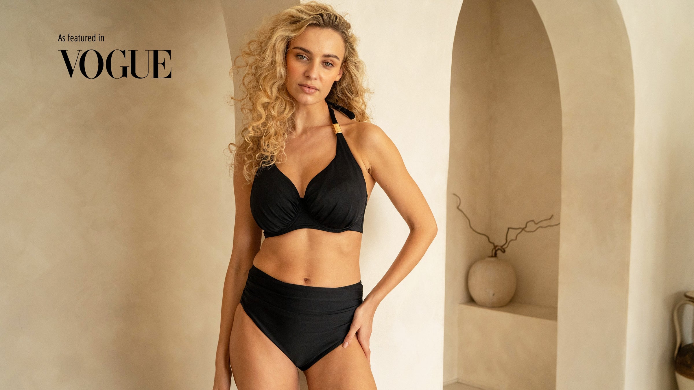 Elegant woman in fuller bust black halterneck bikini with luxurious golden trims with as featured in Vogue text