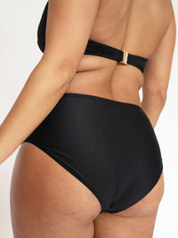 Person wearing a black bikini with a gold clasp on a white background